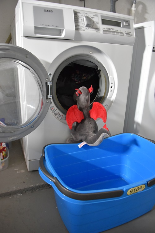 Dracon stopft Wäsche in die Waschmaschine